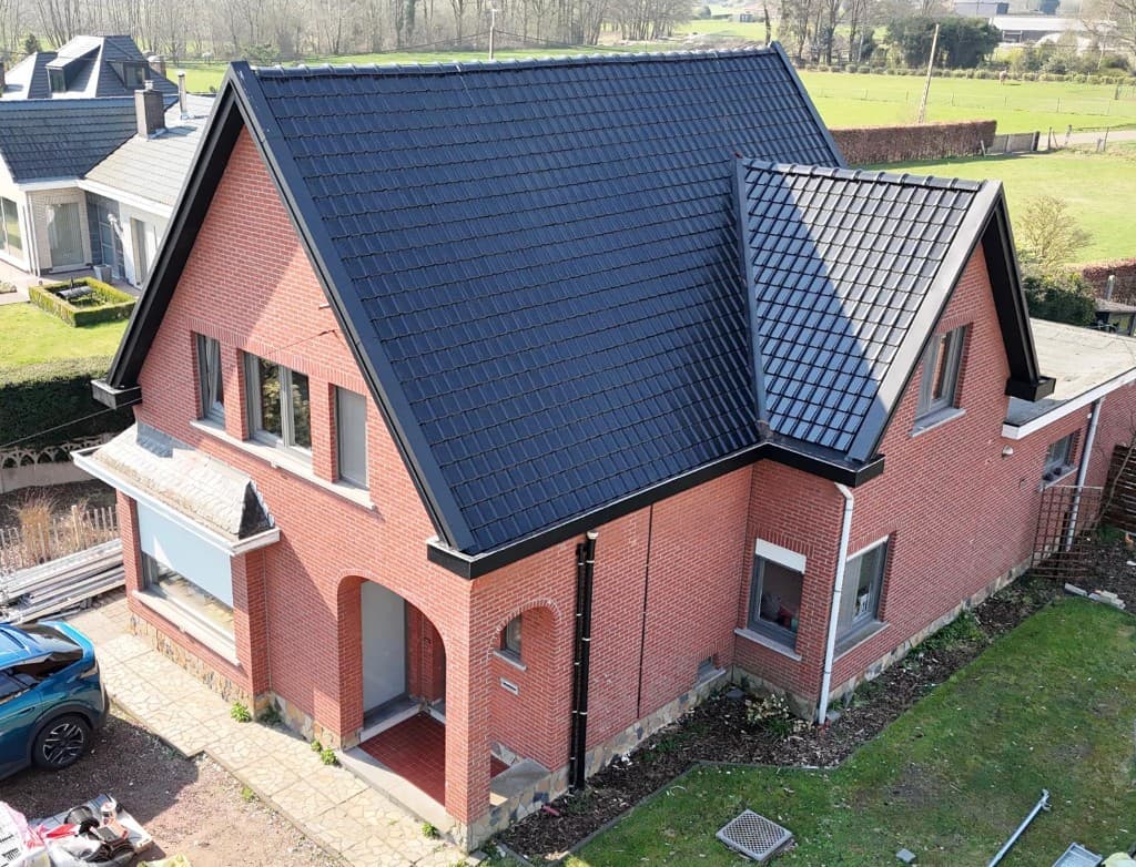 Afgewerkt hellend dak met donkere pannen op een bakstenen woning