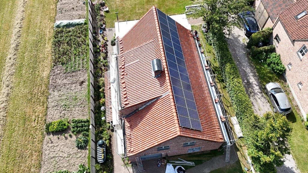 Luchtfoto van een pannendak met groot zonnepanelenvlak en stelling