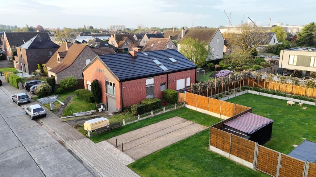 Nieuw hellend dak met donkere pannen en dakramen op een bakstenen woning
