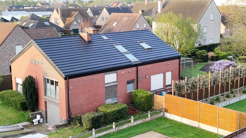 Nieuw donker pannendak met dakramen op een landelijke bakstenen woning