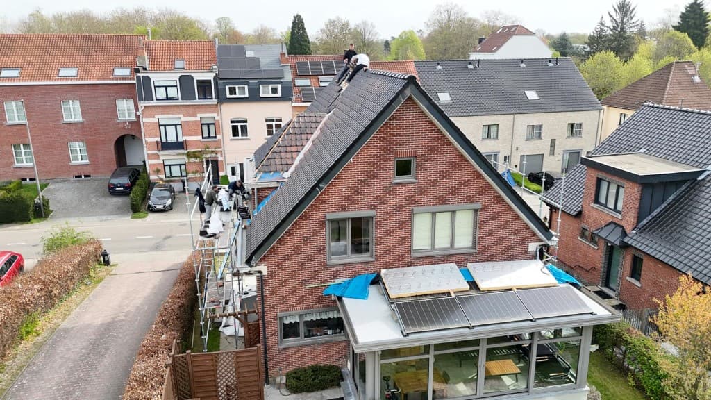 Dakwerkers op de nok tijdens plaatsing van pannen en zonnepanelen