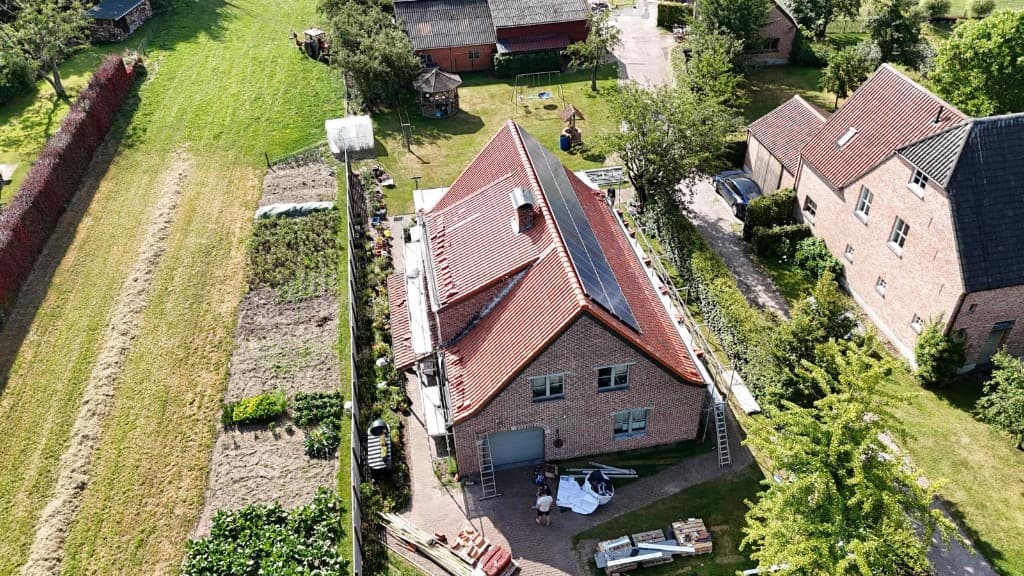 Bakstenen woning met rood pannendak, zonnepanelen en stelling