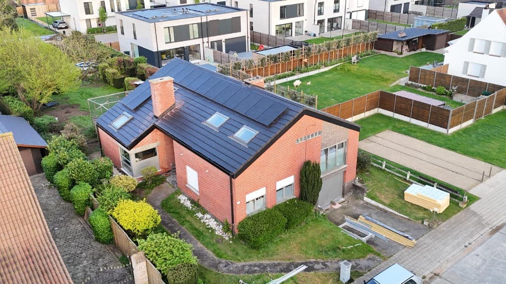 Hellend dak met donkere pannen, dakramen en zonnepanelen