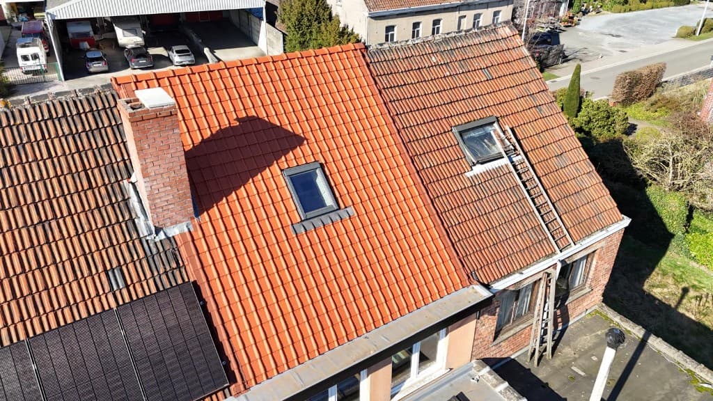 Dakrenovatie in uitvoering: nieuwe terracotta pannen naast het oude dakvlak